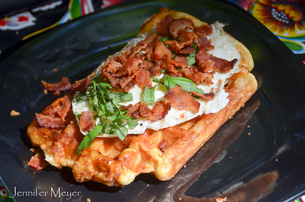 Waffle with fried egg, bacon crumbles, and basil.