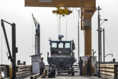 The girls watched this boat hoisted up by crane.