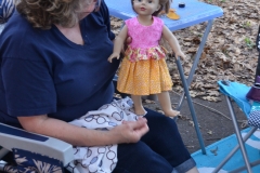 Kate models the doll dress she sewed for Linda's granddaughter.