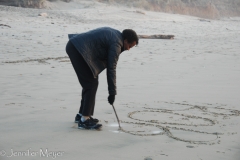Robin writes in the sand.