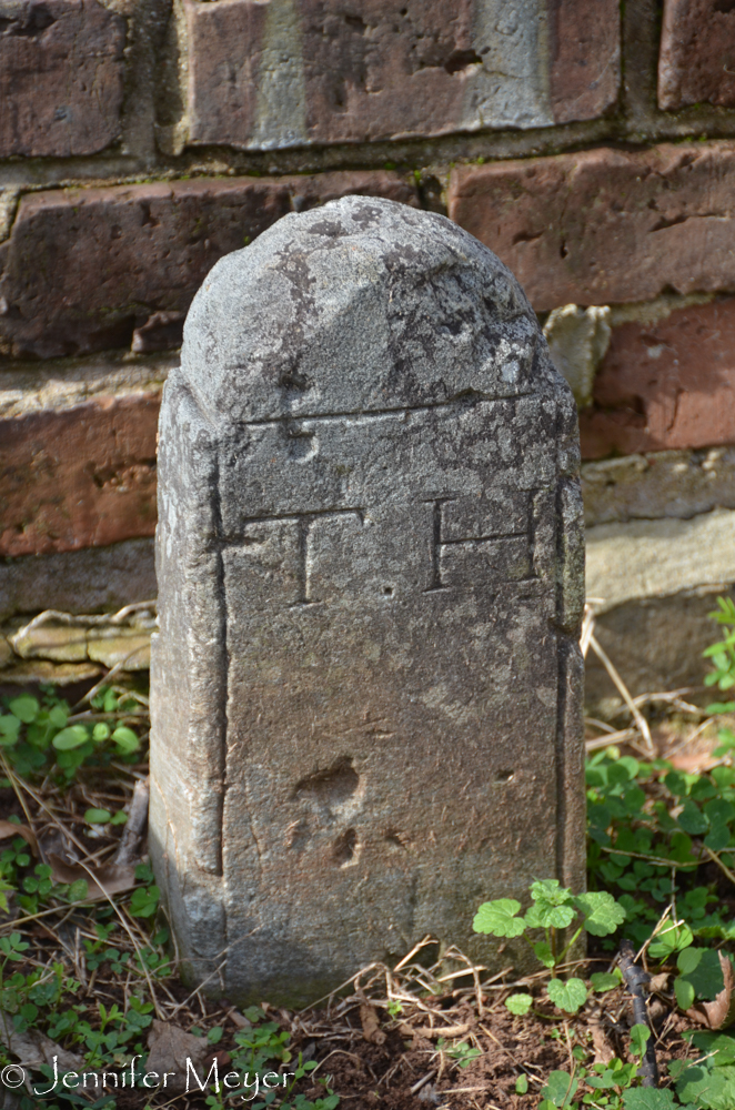 The tiny headstone reads only "TH."