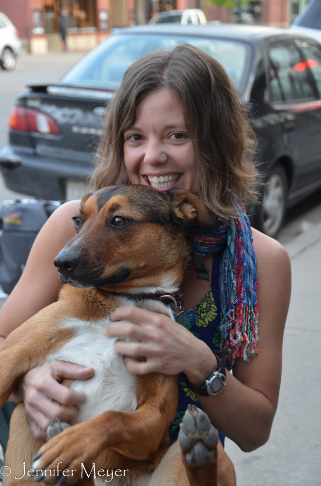 Young woman sitting on a bench cuddling her dog.