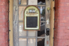 The coffeeshop sign says, "Customers please call... will meet you here in 10 minutes or so."