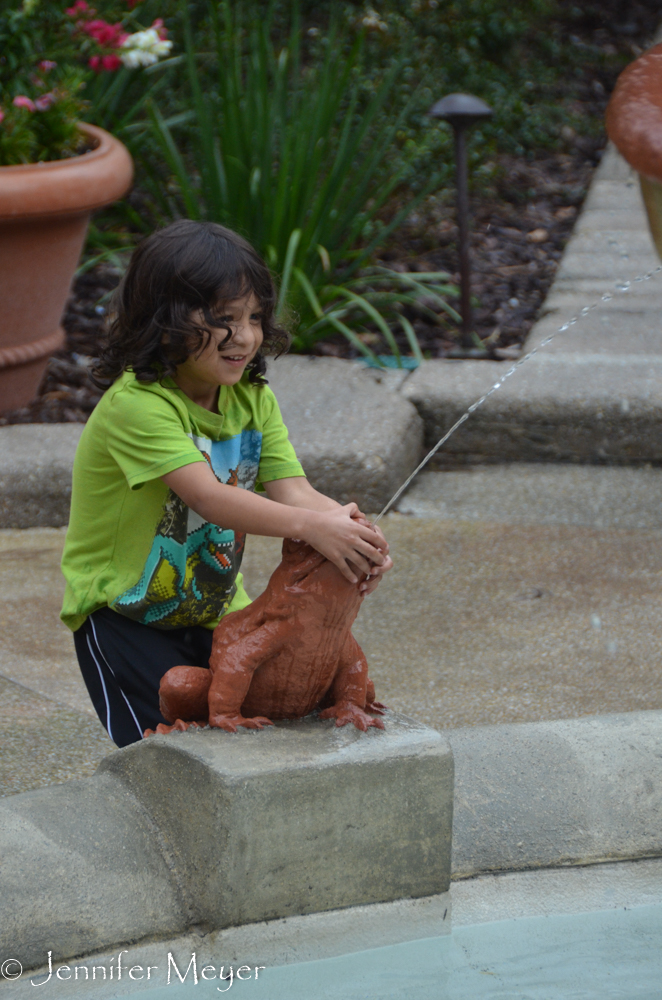 A child plays in the fountain in the rain.