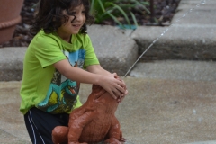 A child plays in the fountain in the rain.