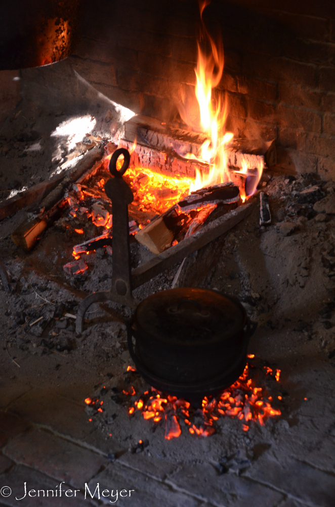 Applesauce is cooked in a bed of coals on the hearth.