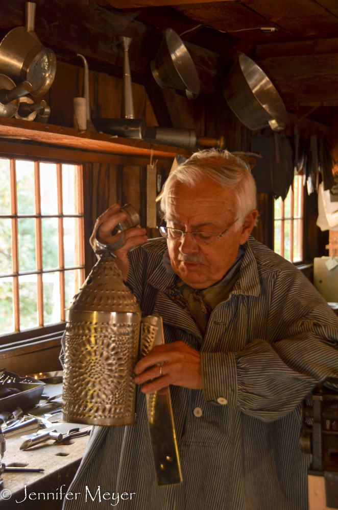 A tinsmith demonstrates a candle lantern.