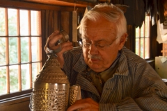 A tinsmith demonstrates a candle lantern.
