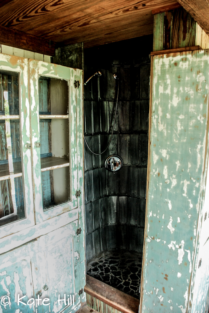 tiny shower with tin tiles and rock floor