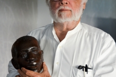 He holds one of ?? 63 heads that will be installed on poles in a new exhibit to depict horrific local history.